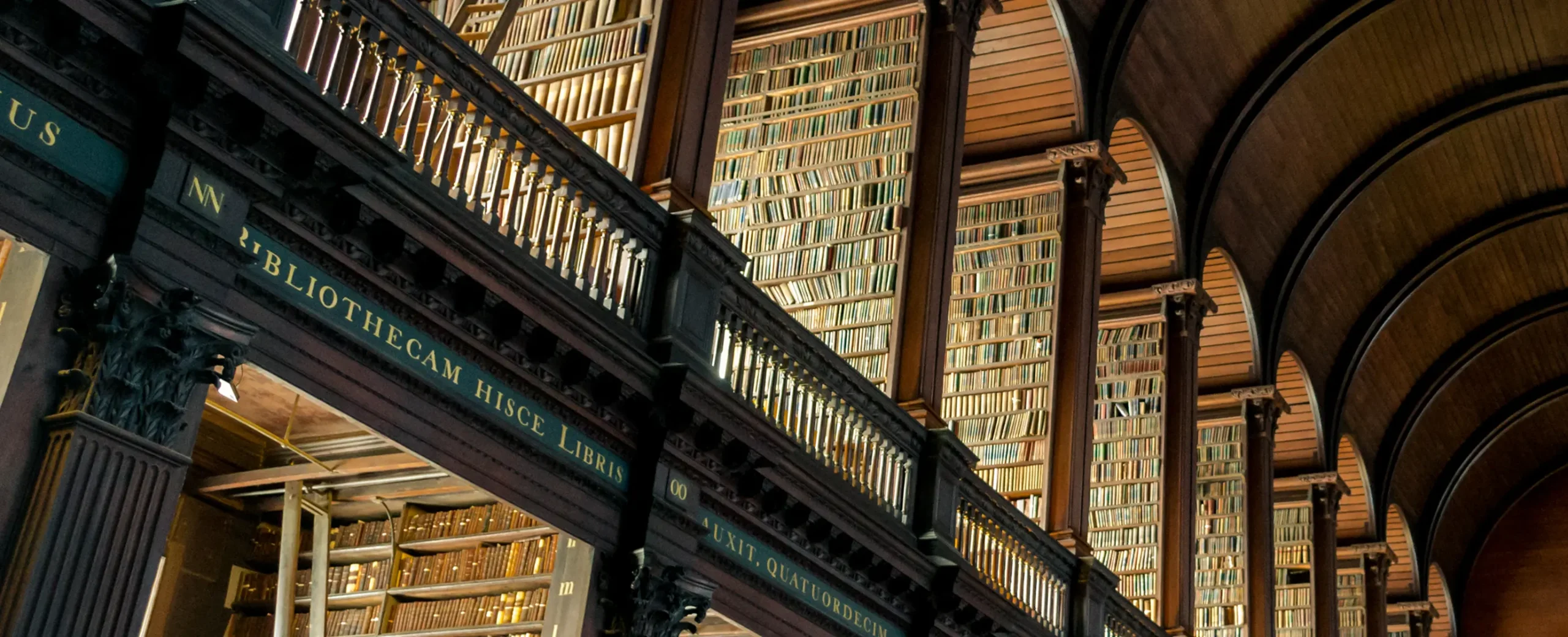 Elegant library interior with arched wooden ceilings, towering bookshelves filled with books, and ornate columns, conveying a sense of timeless knowledge.